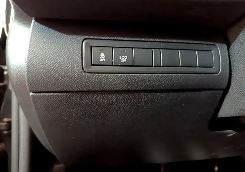 Boutons de commande du système antipatinage et mode ECO sur la console noire côté conducteur d'une Peugeot 308 gris foncé.