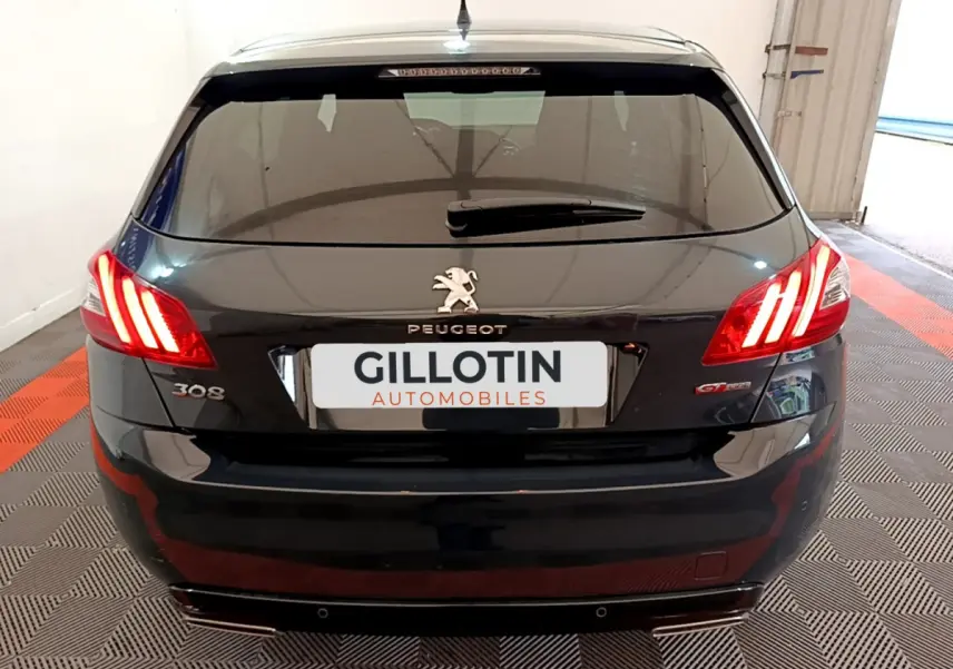 Vue arrière d'une Peugeot 308 gris foncé avec feux LED allumés et badge GT Line visible.