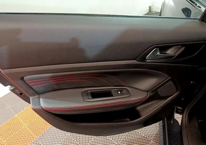 Gros plan sur la porte côté gauche de la Peugeot 308 GT Line 2016 avec surpiqûres rouges et poignée noire.