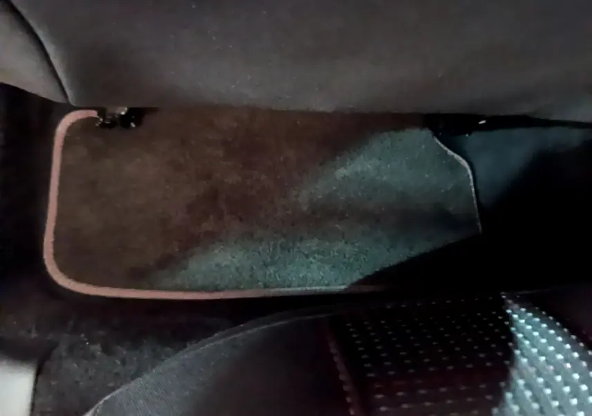 Tapis de sol noir avec bordure beige sous le siège avant dans une Peugeot 308 gris foncé 2016.