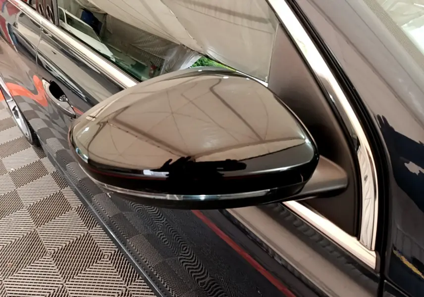 Rétroviseur côté gauche noir brillant de la Peugeot 308 gris foncé, vue rapprochée sur la portière avant.