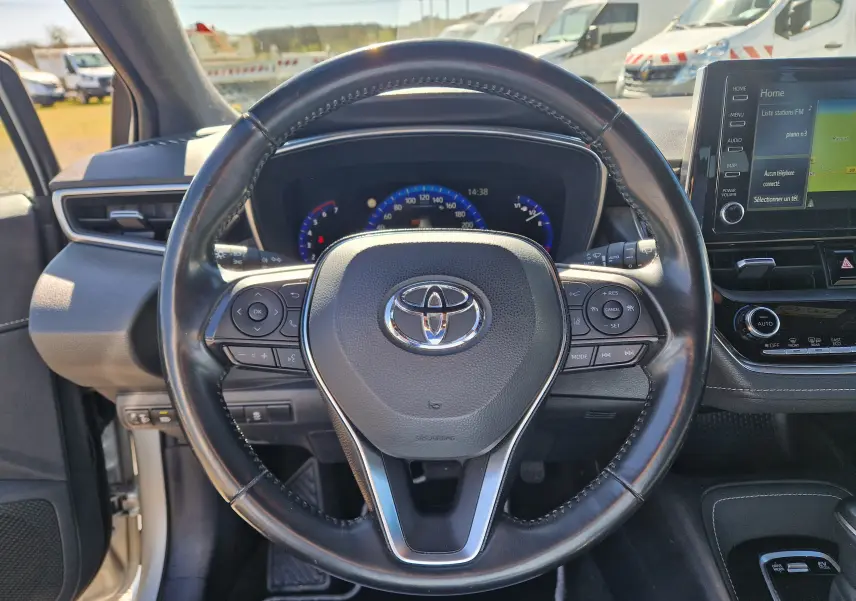 Vue intérieure centrée sur le volant noir de la Toyota Corolla Hybride 122h 2019 avec tableau de bord et écran tactile visibles.