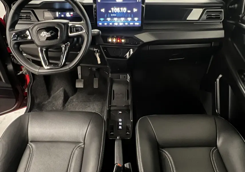 Vue intérieure avant de la LIGIER JS50 BEV 8KWH ELITE 2025, tableau de bord moderne avec écran tactile et sièges noirs.
