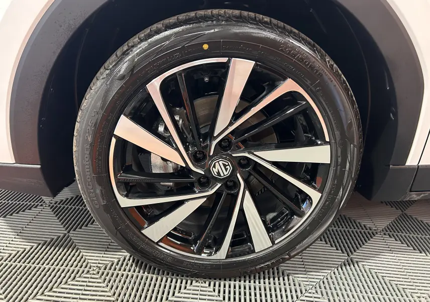 Gros plan sur la roue avant droite du MG ZS Hybrid+ 197 Luxury en blanc Dover, jante alliage bicolore noire et argent.
