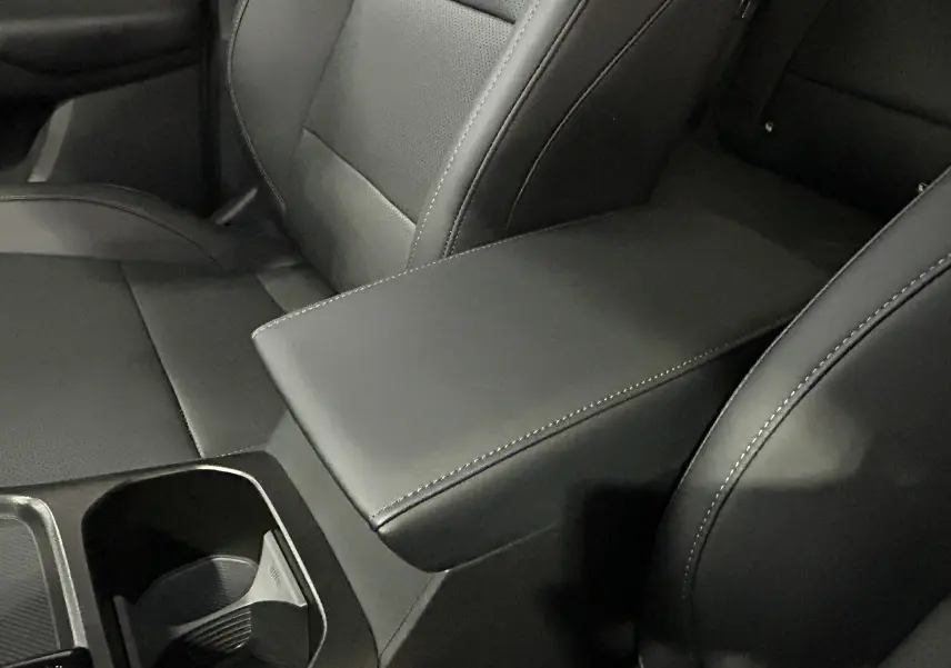 Gros plan sur l'accoudoir central en cuir noir avec surpiqûres blanches entre les sièges avant du MG MOTOR ZS Hybrid+ 2026.