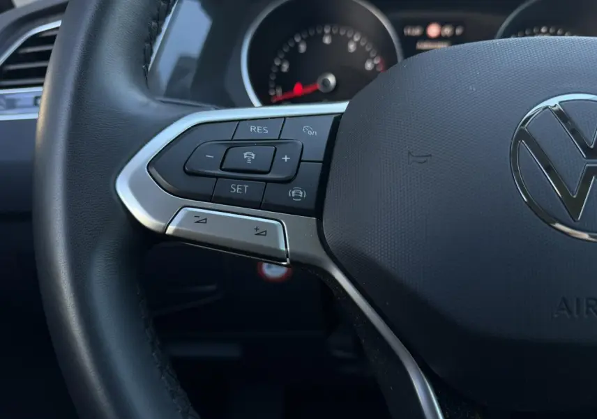 Gros plan sur le volant cuir multifonctions du Volkswagen Tiguan 2024 avec commandes de régulateur adaptatif.