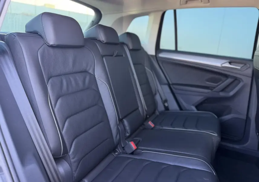 Vue latérale droite de la banquette arrière en cuir noir du Volkswagen Tiguan 2024 avec surpiqûres claires et vitres surteintées.