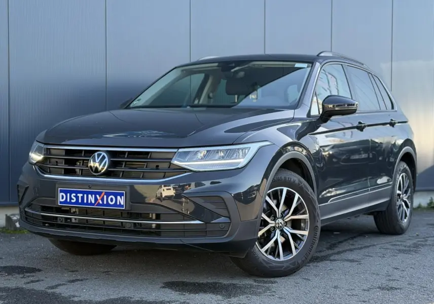 Volkswagen Tiguan 1.5 TSI gris Urano en 3/4 avant droit, avec jantes alliage et calandre distinctive.