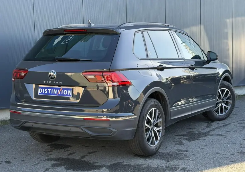 Volkswagen Tiguan 1.5 TSI gris Urano vu en 3/4 arrière droit avec jantes alliage 17 pouces et vitres surteintées.