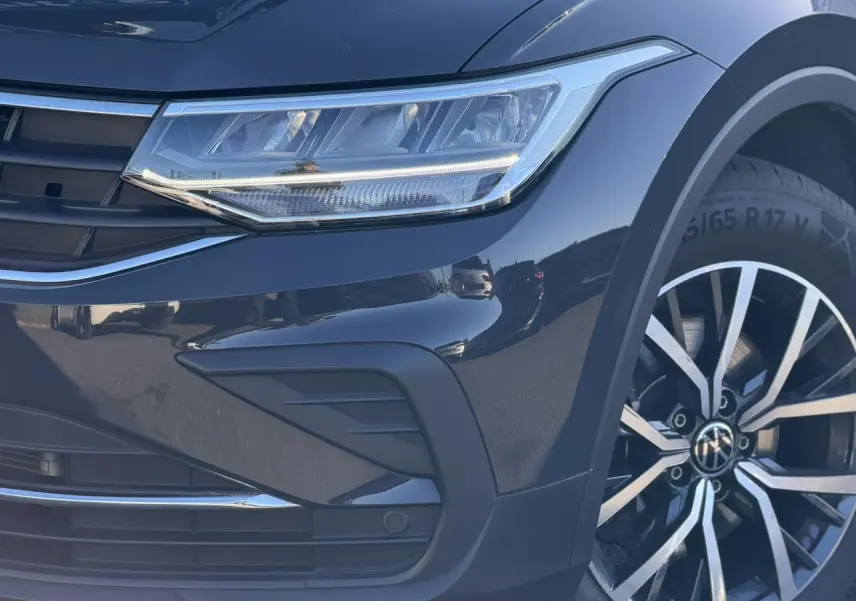 Gros plan sur l'avant droit du Volkswagen Tiguan gris Urano, mettant en valeur le phare LED et la jante alliage 17 pouces.