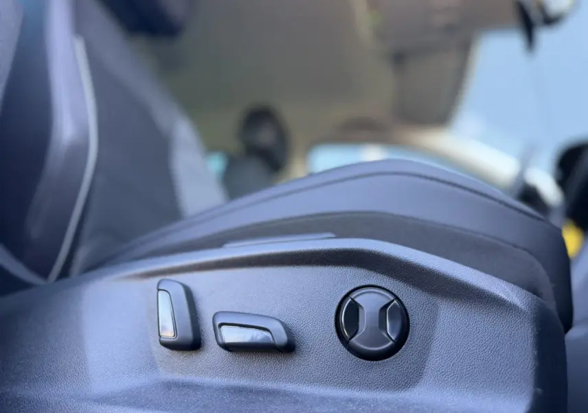 Gros plan sur les commandes de réglage électrique du siège avant côté gauche du Volkswagen Tiguan gris Urano 2024.
