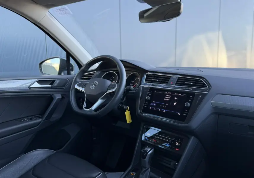 Vue intérieure côté conducteur du Volkswagen Tiguan 2024 avec tableau de bord noir et écran tactile central.