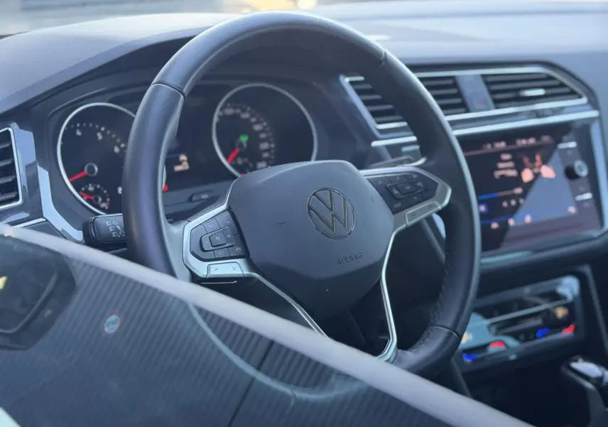 Vue rapprochée du volant cuir multifonctions et du tableau de bord noir du Volkswagen Tiguan 2024.