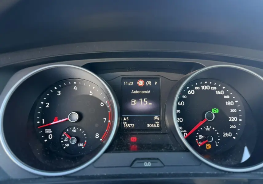 Vue rapprochée du tableau de bord du Volkswagen Tiguan gris Urano 2024, affichant l'autonomie restante de 15 km.