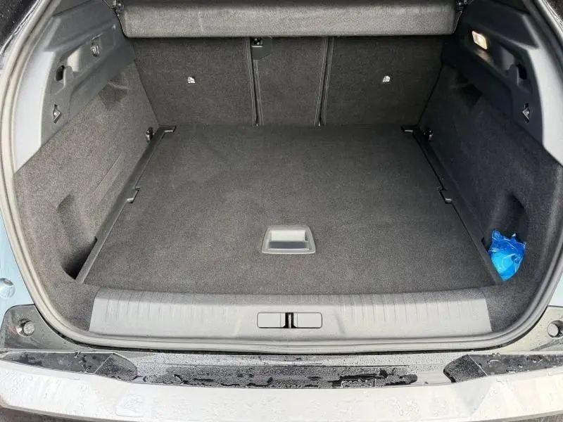 Vue du coffre ouvert d'un Peugeot 3008 électrique bleu 2024, montrant un espace de rangement propre et spacieux.