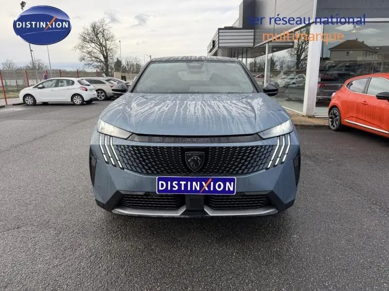 Vue de face du Peugeot 3008 électrique bleu avec calandre noire et feux LED distinctifs, stationné devant un showroom.