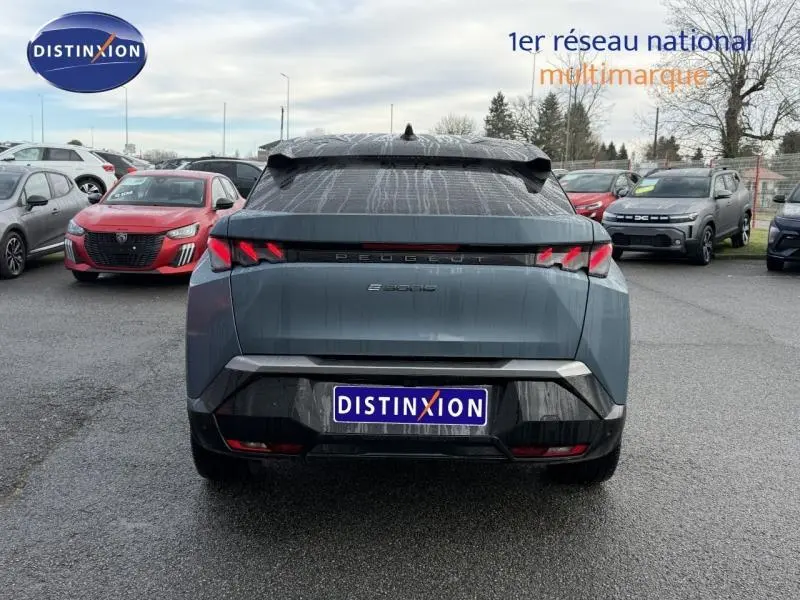 Vue arrière d'un Peugeot 3008 électrique bleu avec feux arrière LED en forme de griffes, stationné en extérieur.