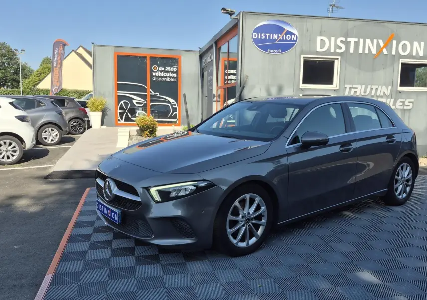 Mercedes Classe A 180d gris foncé vue 3/4 avant droit, avec jantes alliage et calandre distinctive au logo central.