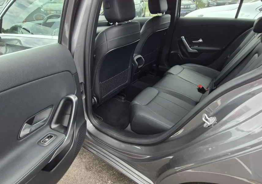 Vue côté gauche arrière montrant l’intérieur cuir noir et la porte ouverte d’une Mercedes Classe A 180d gris foncé 2020.