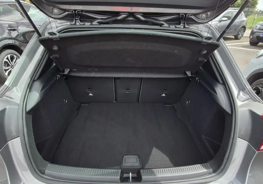 Coffre ouvert vu de l'arrière d'une Mercedes Classe A 180d gris foncé, montrant l'espace de chargement vide.
