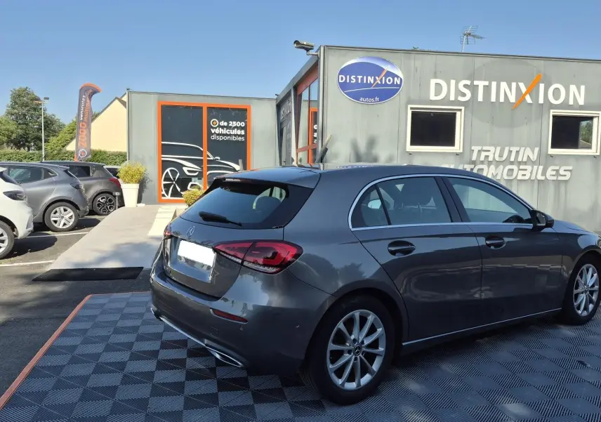 Vue 3/4 arrière droite d'une Mercedes Classe A 180d gris foncé, avec jantes alliage et feux arrière LED visibles.