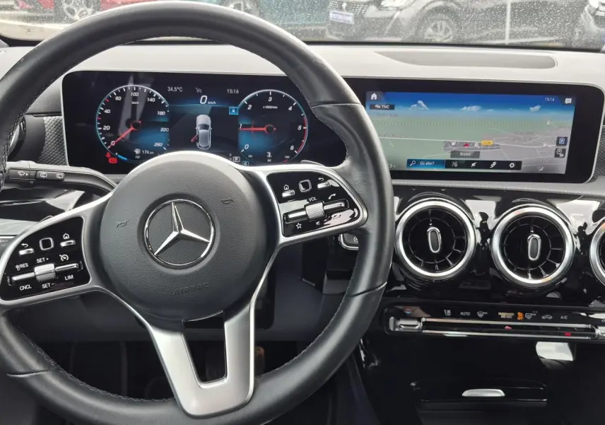 Vue intérieure centrée sur le volant cuir noir et le tableau de bord numérique avec écran tactile du Mercedes Classe A 180d gris foncé.