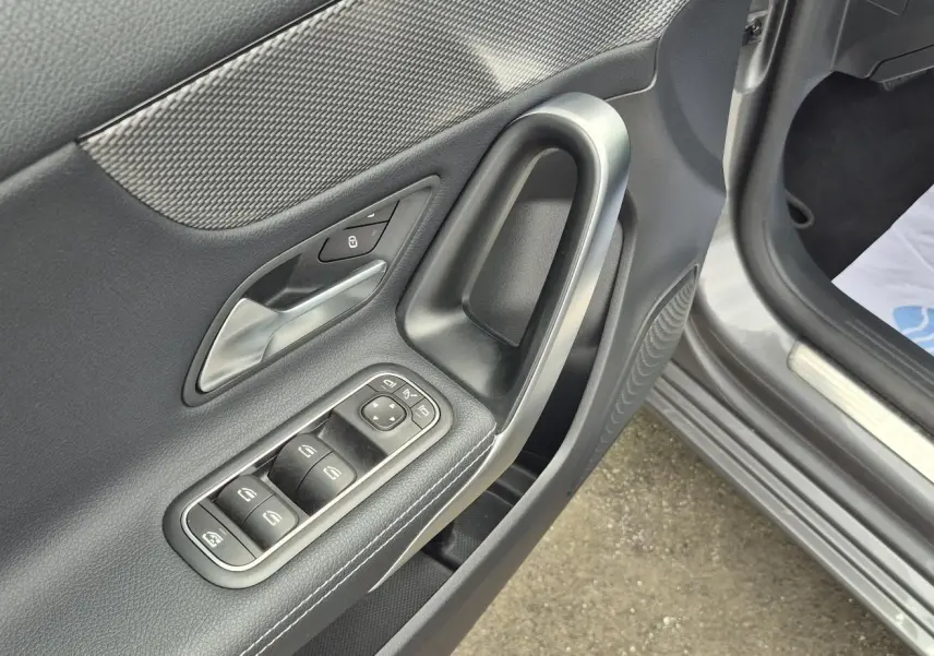 Gros plan sur la porte avant gauche gris foncé d'une Mercedes Classe A 180d 2020, avec commandes électriques et poignée argentée.