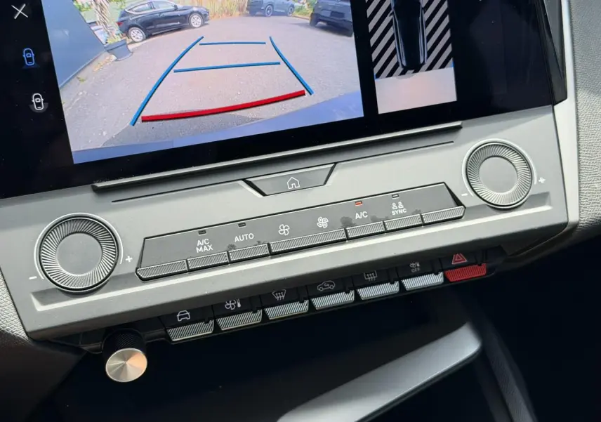 Détail de la console centrale du Peugeot 308 SW 2025 avec écran tactile affichant la caméra de recul et commandes climatisation grises.