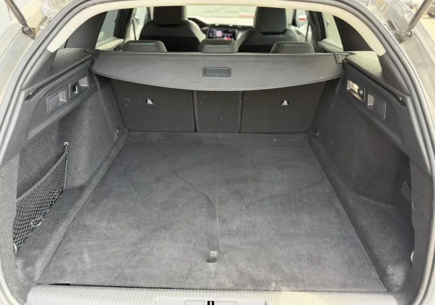 Coffre spacieux de Peugeot 308 SW gris Selenium vu de l'arrière avec cache-bagages et banquette rabattue partiellement visible.