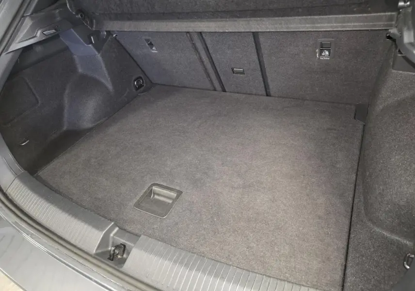 Coffre spacieux vu de face, intérieur gris foncé, plancher plat et habillage tissu dans un Volkswagen T-Roc 2025.