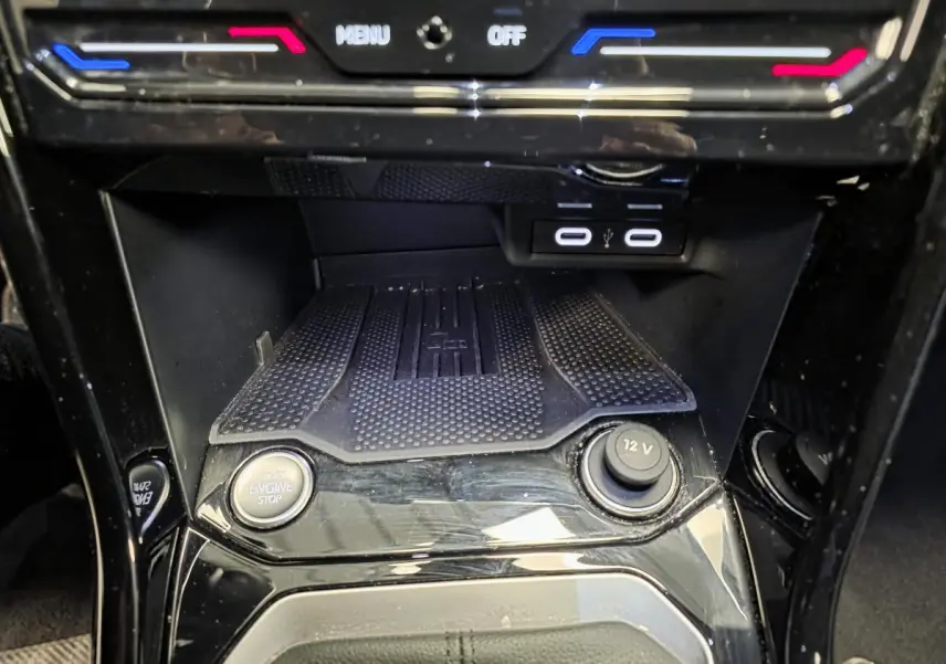 Détail de la console centrale noire brillante du Volkswagen T-Roc 1.5 TSI R-Line avec boutons start/stop et prise 12V visible.