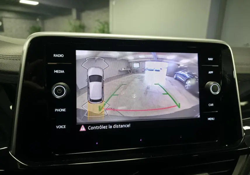 Écran tactile affichant la caméra de recul du Volkswagen T-Roc gris avec repères de stationnement en garage.