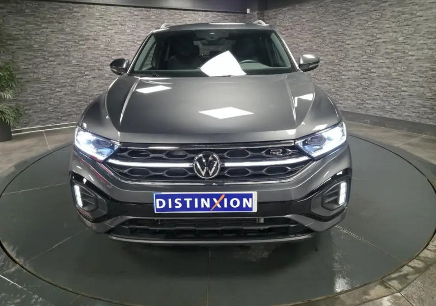 Vue avant d'un Volkswagen T-Roc gris métallisé 2025 avec calandre R-Line et phares Matrix LED allumés.