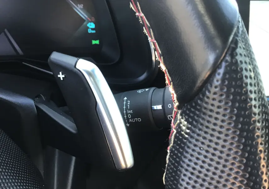 Gros plan sur la palette de changement de vitesse droite en aluminium et cuir perforé du volant noir du DS7 Crossback 2023.