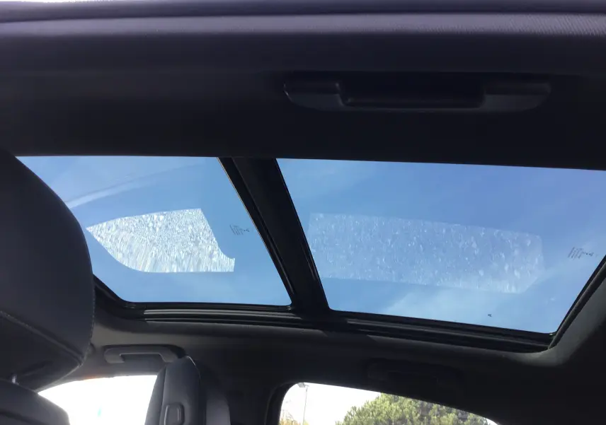 Toit panoramique en verre vu de l'intérieur du DS7 Crossback noir, avec sièges avant en cuir visibles.