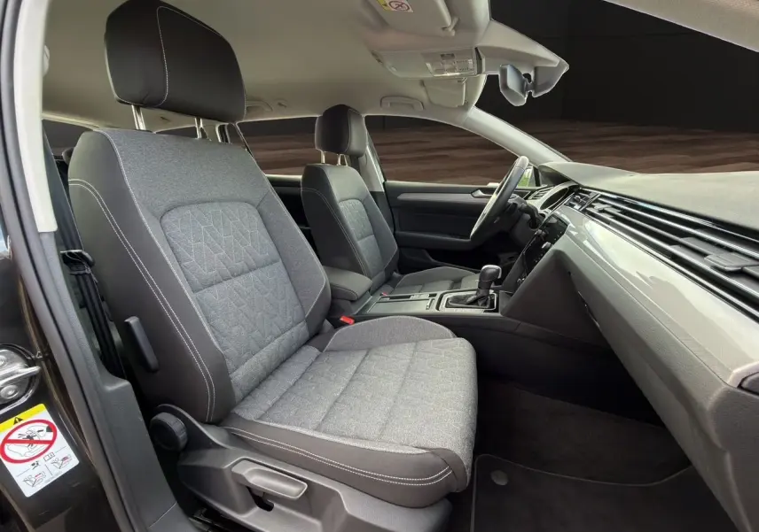 Vue intérieure côté conducteur de la Volkswagen Passat SW 2.0 TDI 2022 avec sièges tissu gris et tableau de bord épuré.