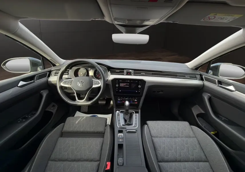 Vue intérieure avant de la Volkswagen Passat SW 2022, tableau de bord moderne et sièges tissu gris noir.