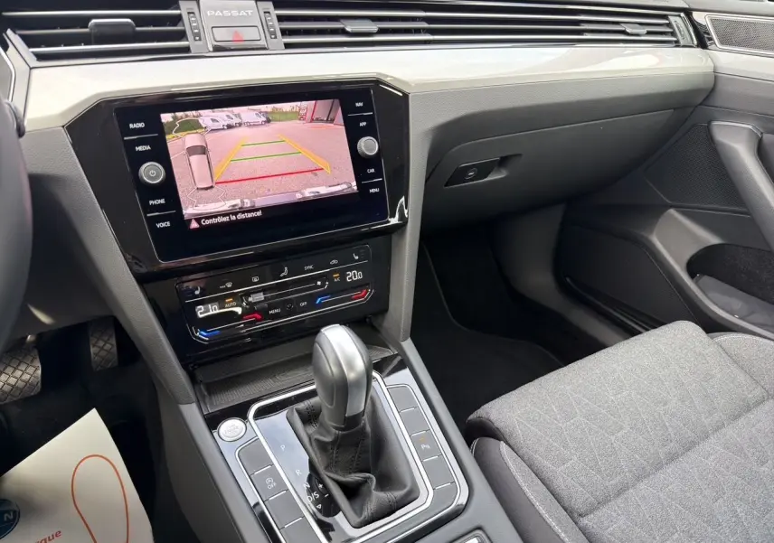 Vue intérieure centrée sur la console centrale et l’écran tactile affichant la caméra de recul de la Volkswagen Passat SW gris manganèse.