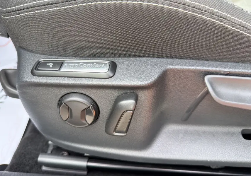 Gros plan sur les commandes de réglage siège tissu gris noir de la Volkswagen Passat SW 2.0 TDI Business.