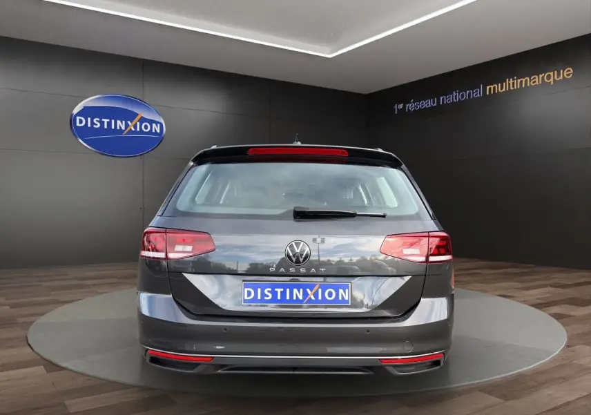 Vue arrière d'une Volkswagen Passat SW gris manganèse avec caméra de recul, sur fond intérieur showroom.