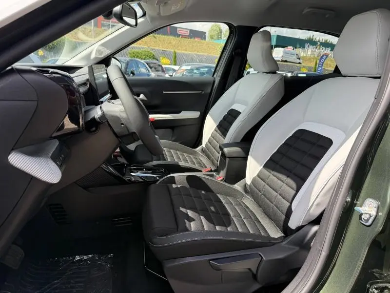 Vue intérieure côté conducteur de la Citroën C3 Aircross 2026, sièges bicolores gris clair et noir, volant multifonction visible.