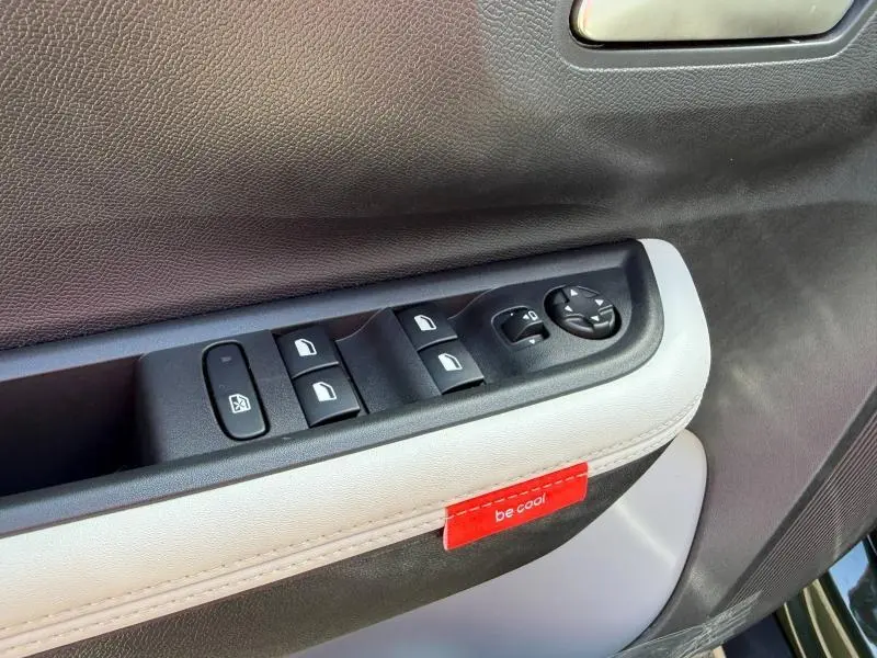 Détail des commandes de lève-vitres côté conducteur avec insert blanc et étiquette rouge "be cool" dans une Citroën C3 Aircross Vert Montana.
