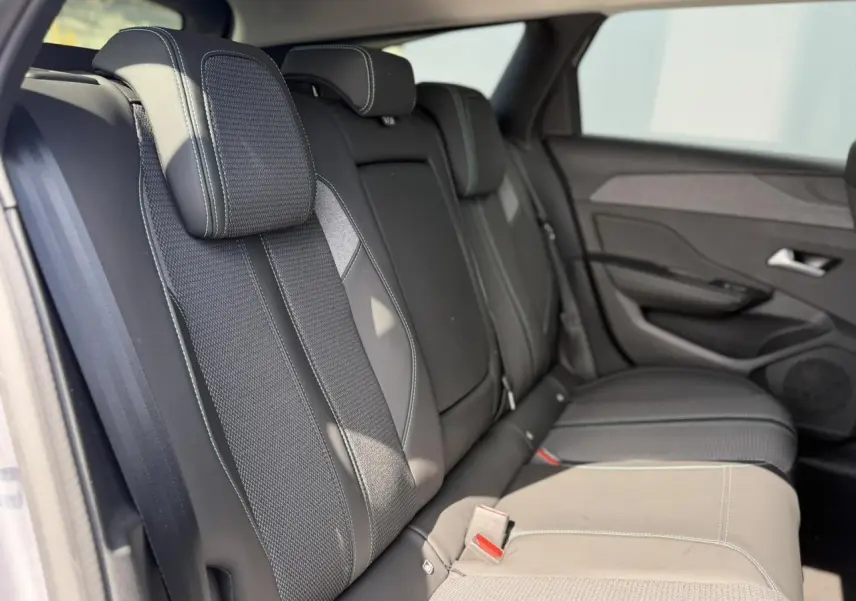Vue latérale droite des sièges arrière en sellerie tri matières gris foncé avec surpiqûres bleues du Peugeot 308 SW 2025.