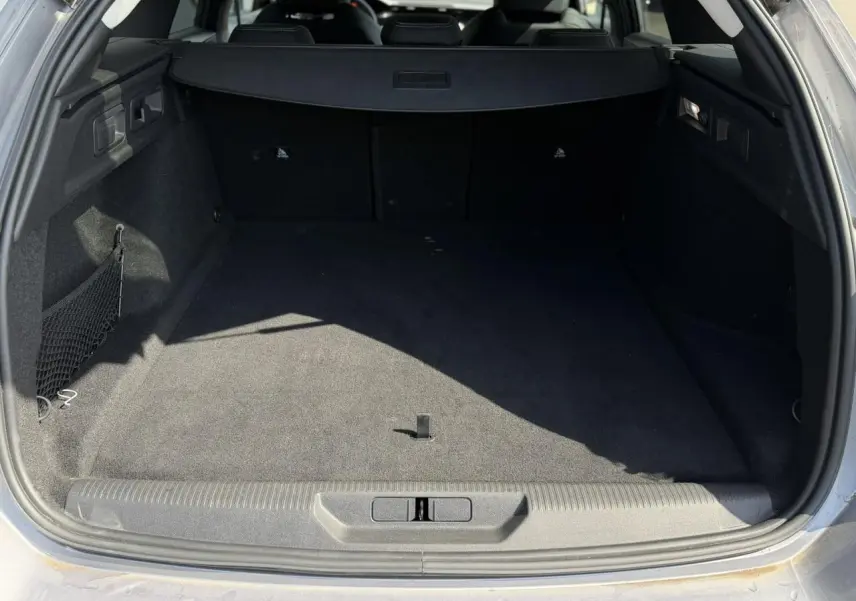 Coffre ouvert d’un Peugeot 308 SW gris Artense, montrant un espace de chargement vide et tapis noir.