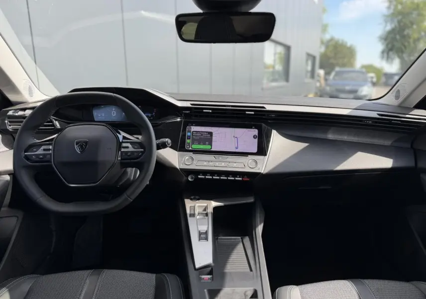 Vue intérieure avant du Peugeot 308 SW 2025 avec tableau de bord noir et écran tactile central lumineux.
