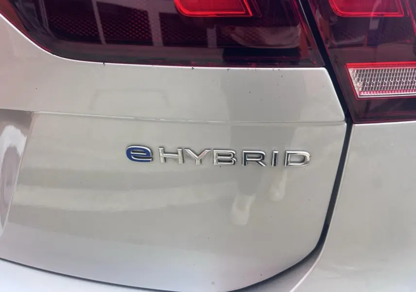 Gros plan sur le logo eHybrid à l'arrière droite d'un Volkswagen Tiguan gris dauphin métallisé.