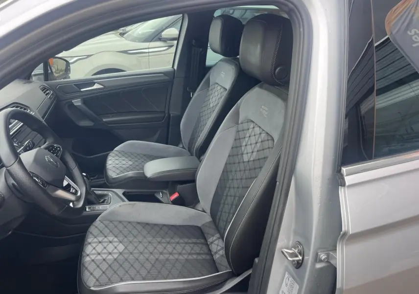Vue intérieure côté conducteur du Volkswagen Tiguan gris dauphin, sièges sport R-Line avec surpiqûres contrastées.
