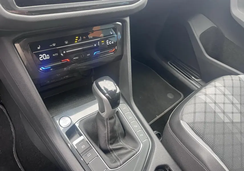 Vue intérieure centrée sur la console centrale du Volkswagen Tiguan gris Dauphin avec levier de vitesse et commandes climatiques.