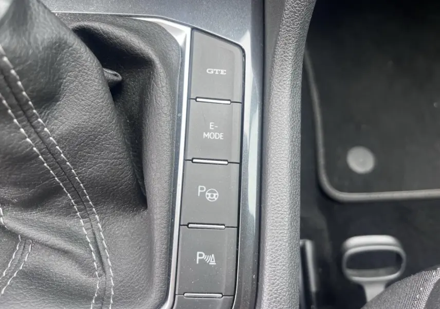 Gros plan sur les boutons de commande du mode GTE et E-MODE dans l’habitacle noir du Volkswagen Tiguan gris dauphin.