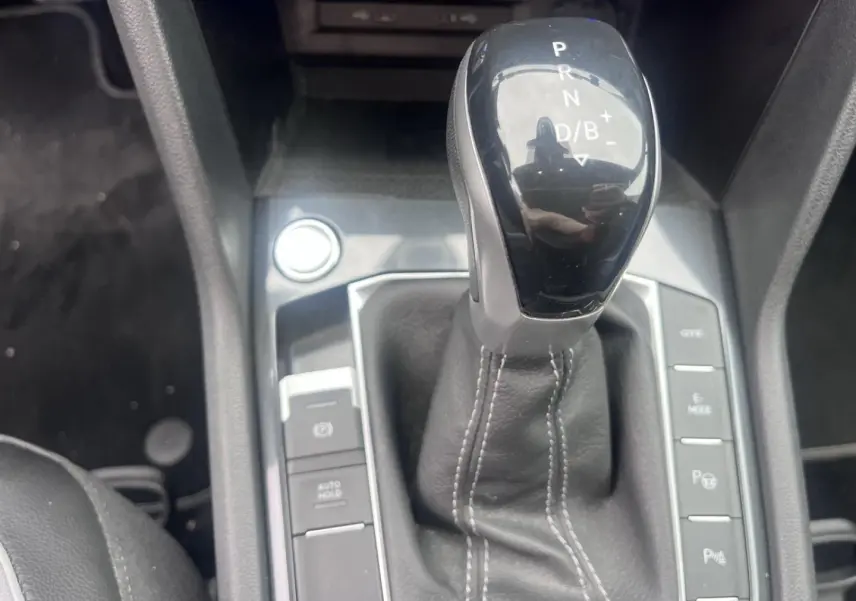 Le levier de vitesse automatique noir du Volkswagen Tiguan 1.4 eHybrid vu en gros plan, entouré de boutons de contrôle.